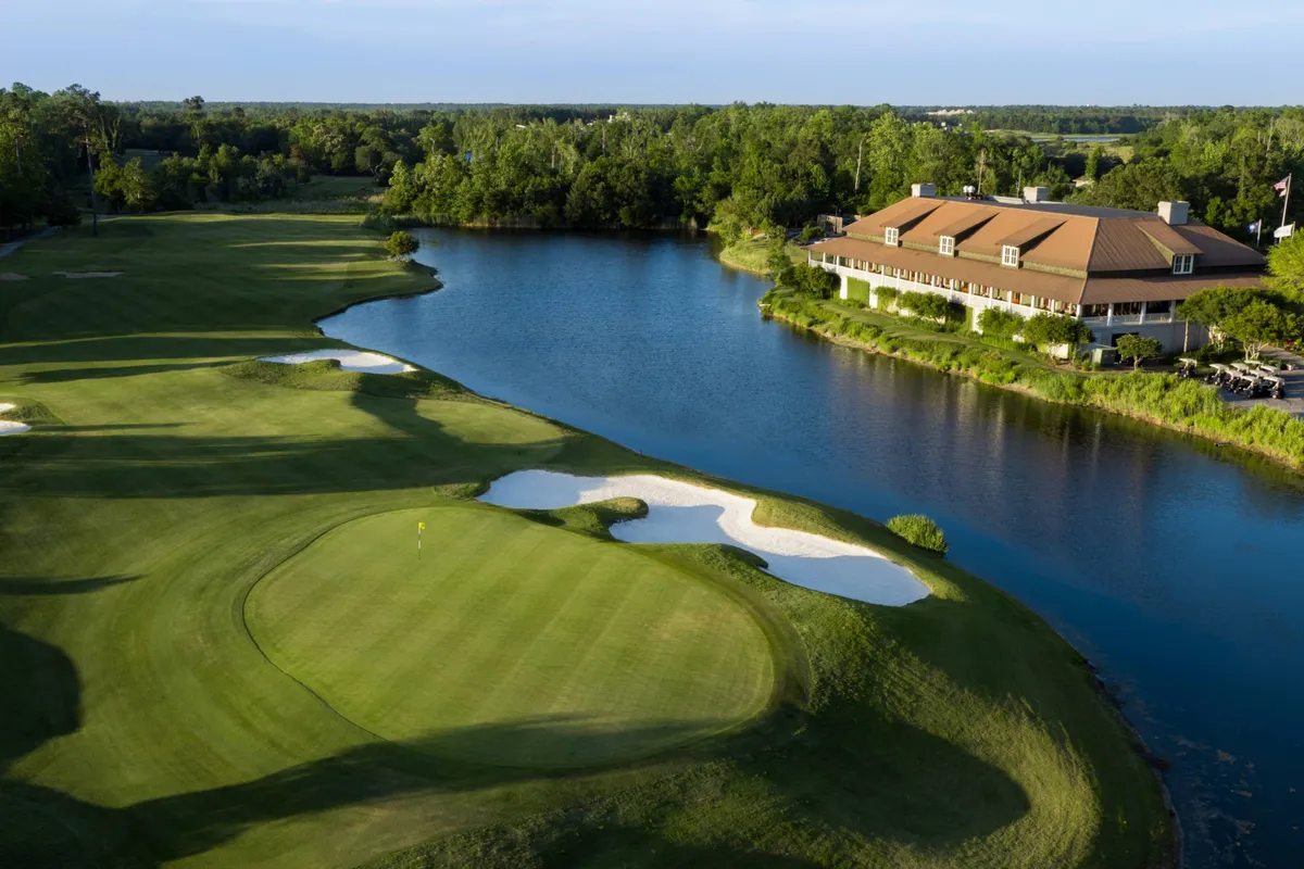 A sweeping exterior view of a lush golf course bordered by a tranquil lake, with a stately clubhouse visible in the background. The scene is bathed in warm sunlight, inviting guests to enjoy recreational activities in a peaceful setting.