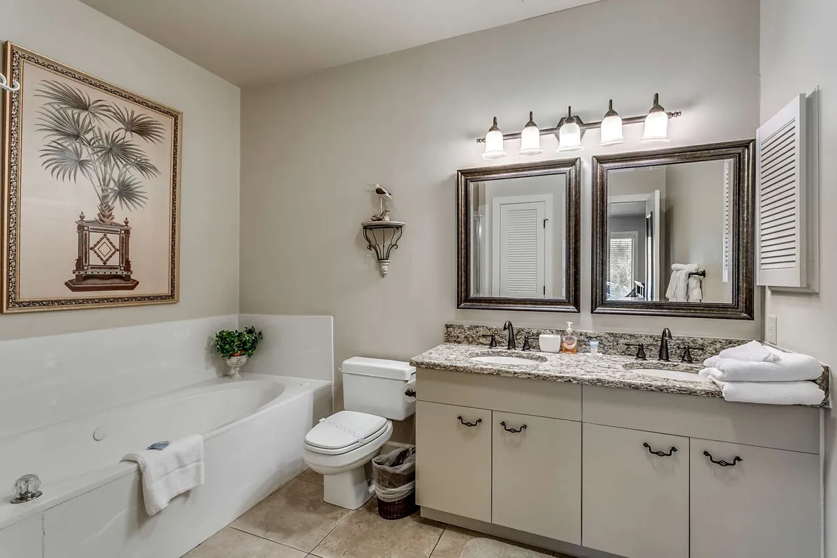 A tranquil bathroom featuring a bathtub, vanity with mirrors, tasteful framed art, and soft lighting. The mood is peaceful, offering a comfortable setting for relaxation and self-care after a busy day.