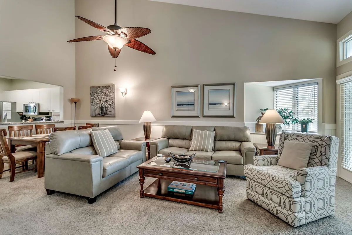 A cozy seating arrangement in a living room, featuring comfortable sofas, a coffee table, and a ceiling fan. The space feels inviting and is positioned to suggest relaxation after a day outdoors.