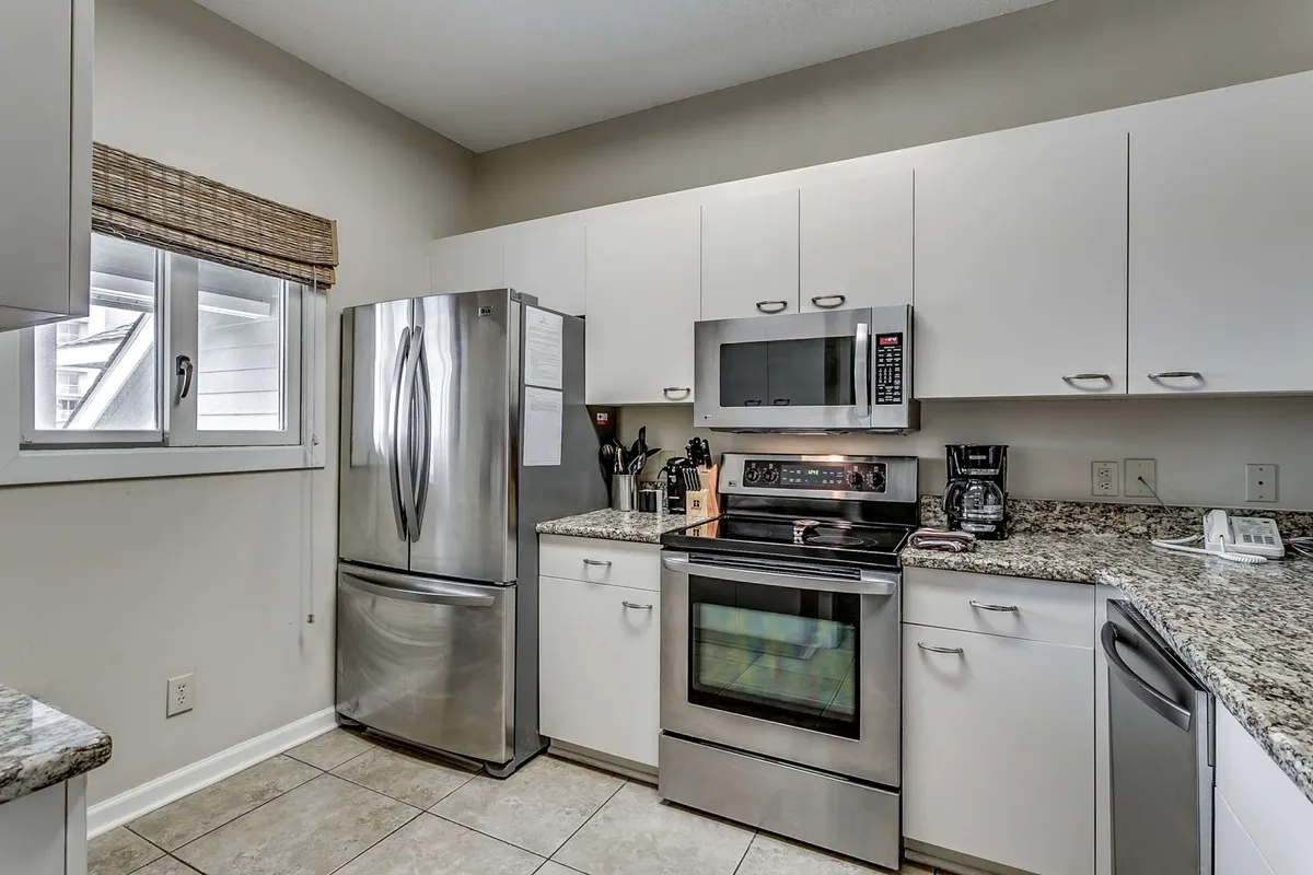 A spacious kitchen with stainless steel appliances, granite countertops, and ample cabinetry. The space is set up for group cooking, with plenty of counter space for preparing meals and gathering together. Natural light flows in, adding to the inviting and functional atmosphere.