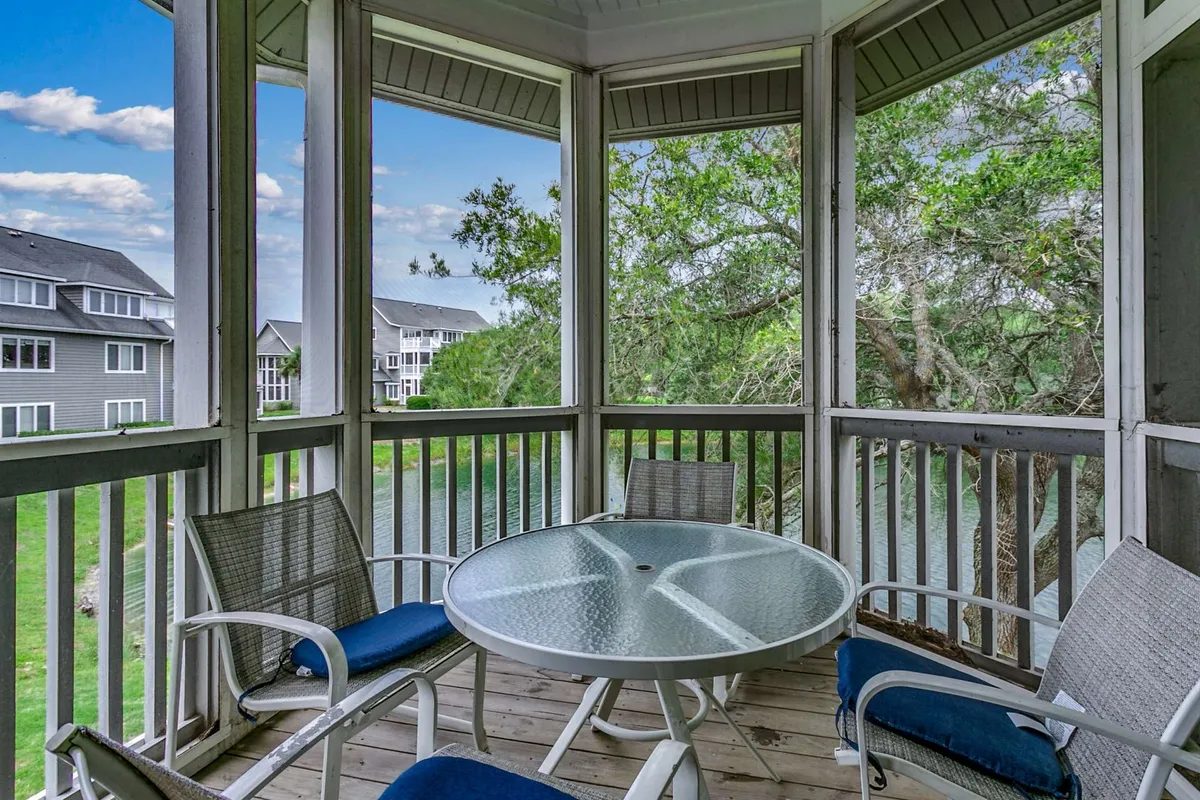 A bright screened back porch with a round glass table, comfortable chairs, and views of the pond. The space is perfect for morning coffee, reading, or quiet relaxation while enjoying fresh air and soothing views.